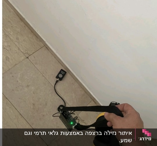 אדם מחזיק מכשיר לגילוי נזילות עם אוזניות